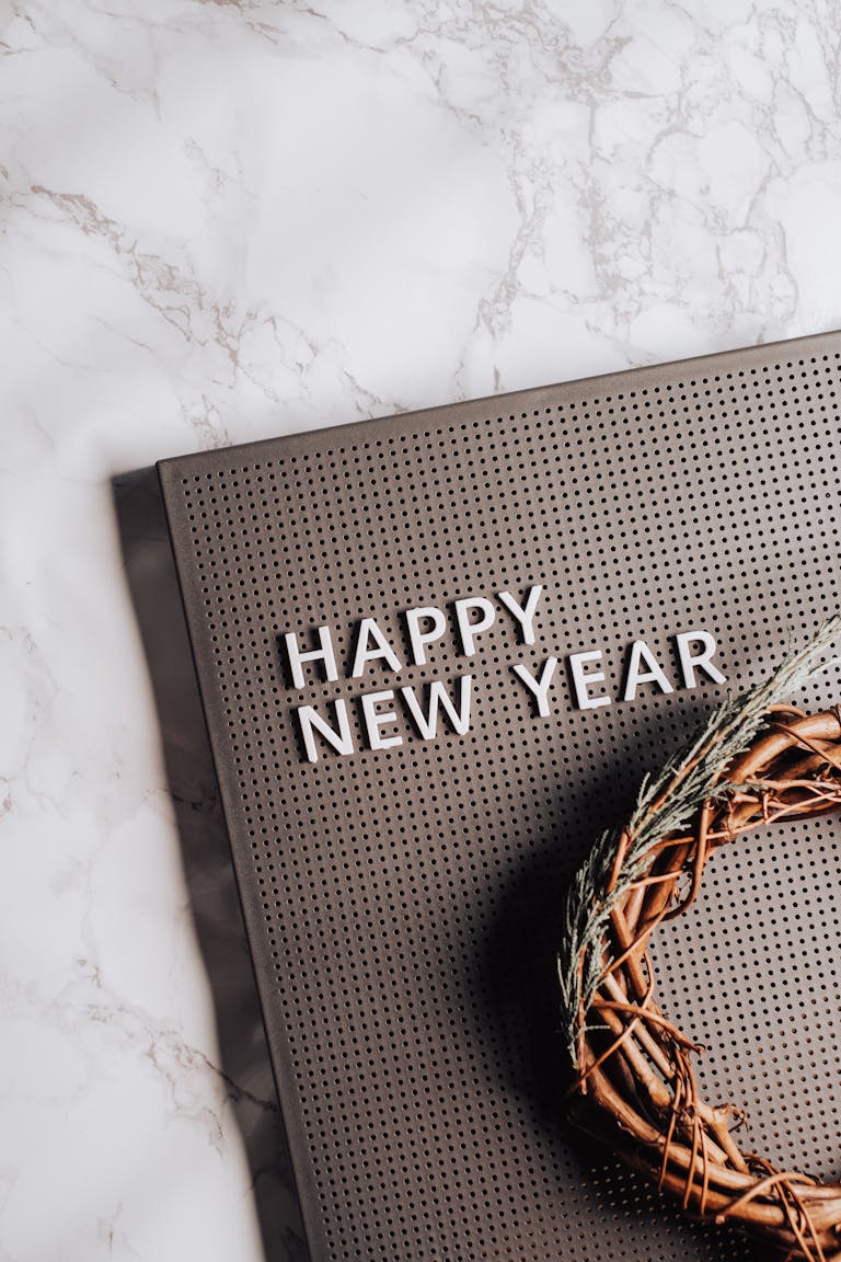Wooden wreath and pegboard displaying 'Happy New Year' on marble surface.